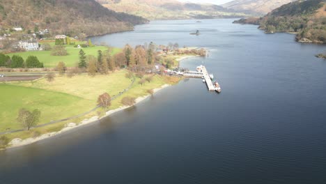 Drone-panning-from-the-left-to-the-right-side-of-the-frame-in-front-of-a-jetty-by-the-lakeside-of-Ullswater-Lake-in-Cumbria,-England-in-United-Kingdom