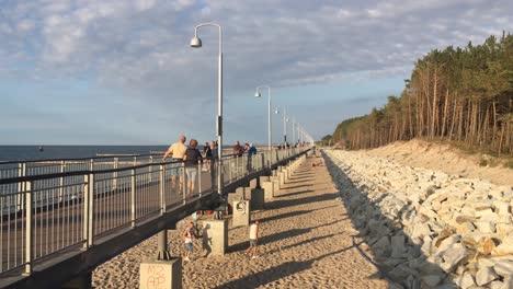 Promenada-Przyjazni-Brücke-In-Mielno,-Polen-An-Der-Küste-Der-Ostsee-Bei-Sonnenuntergang-Mit-Passanten