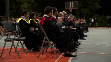 La-Clase-De-Graduados-De-2023-Aplaude-Después-De-Un-Discurso-En-Una-Universidad-Mexicana-Con-Vestidos-Negros,-Rojos-Y-Amarillos.