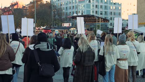 Large-group-of-people-with-signs-participating-in-a-women's-rights-march-in-Stockholm,-Sweden,-in-daylight