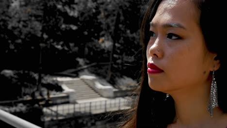 Attractive-Asian-woman,-playing-with-and-brushing-back-hair-in-extreme-close-up,-slowmotion-shot