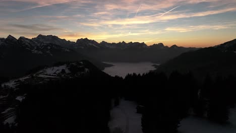 Drones-Que-Vuelan-Sobre-Las-Montañas-En-El-Valle-Son-Nubes-De-Niebla-Y-En-La-Distancia-Altas-Montañas-Con-Nieve-En-Amden,-Weesen,-Glarus,-Suiza,-Estado-De-ánimo-Del-Amanecer