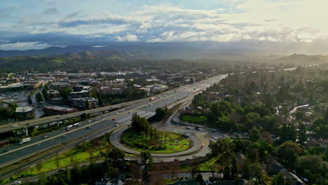 Aerial-view-of-cityscape,-drone-panning-left-above-highway,-ecocity-panoramic-view