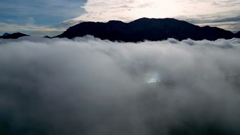 Majestuoso-Pico-De-Montaña-Cubierto-De-Nieve,-Atravesando-Un-Mar-De-Nubes-Blancas-Y-Esponjosas-En-Un-Día-Nublado-Desde-Arriba-Entre-Las-Nubes