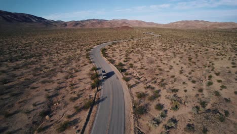 Una-Furgoneta-Mercedes-Sprinter-Que-Recorre-Una-Carretera-Sinuosa-En-El-Parque-Nacional-Joshua-Tree-Mientras-Un-Dron-Orbita-A-Su-Alrededor