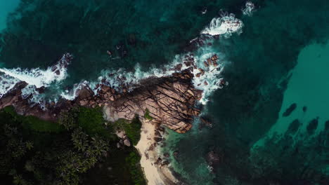Top-down-aerial-view-of-granite-rock-formations-extending-into-the-ocean