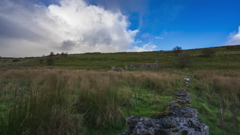 Timelapse-of-rural-nature-farmland-with-stonewall-line-in-the-foreground-located-in-grass-field-during-cloudy-rainbow-day-viewed-from-Carrowkeel-in-county-Sligo-in-Ireland