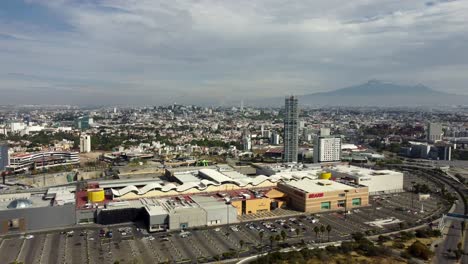 Angelopolis-Lifestyle-Center-with-parking-area-and-cityscape-of-Puebla-City-in-summer,-Mexico