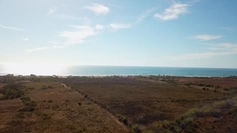 Drone-shot-of-the-Coast-of-Sinaloa,-sunny,-afternoon,-ocean,-fields,-beach,-road