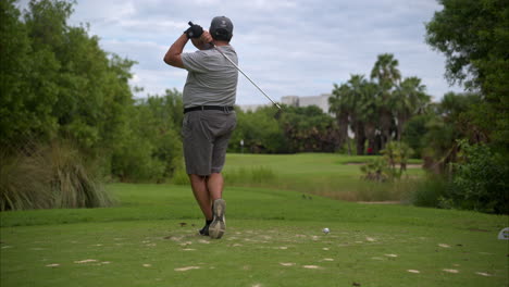 Cámara-Lenta-De-Un-Golfista-Latino-Mexicano-Con-Exceso-De-Peso-Vestido-De-Gris-Haciendo-Un-Swing-De-Práctica-En-Un-Campo-De-Golf