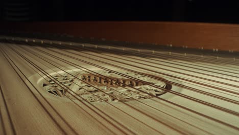 grand-piano-strings,-slight-camera-movement-to-the-right,-closeup,-dark,-yellow-wood