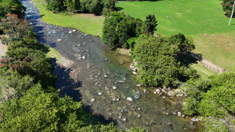 Aerial-birds-eye-shot-of-stream-with-rocks-in-beautiful-landscape-with-sunlight
