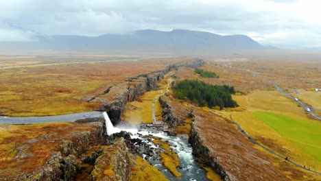 Tomas-Aéreas-De-Drones-De-4k-De-Una-Cascada-En-Medio-De-La-Colorida-Islandia,-Paisaje-Escénico,-Terreno-Y-Tranquilo