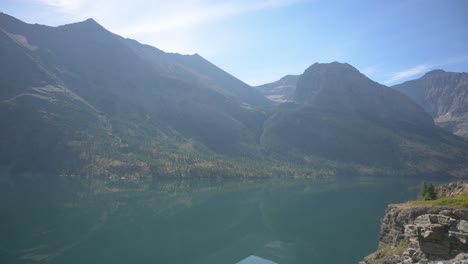 Cloud-reflecting-on-calm-St-Mary-Lake-in-Glacier-National-Park,-pan-left