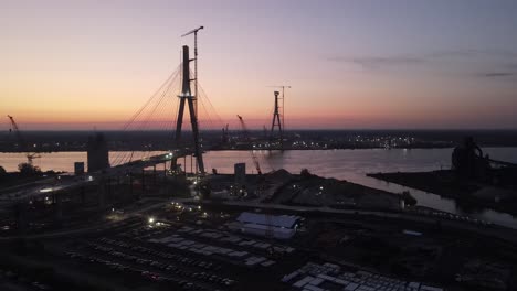 Silhouette-of-international-bridge-of-Gordie-Howe-construction-site-during-sunset,-aerial-view