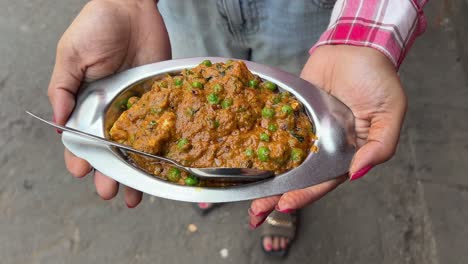 Traditional-vegetarian-curry-paneer-matar-sabji-masala-held-by-a-girl