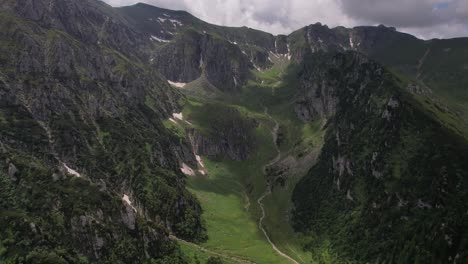 Lush-Malaiesti-Valley-in-Bucegi-Mountains-with-vibrant-green-slopes-and-trails,-aerial-view
