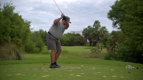 Cámara-Lenta-De-Un-Golfista-Latino-Mexicano-Con-Exceso-De-Peso-Vestido-De-Gris-Golpeando-La-Pelota-Con-Fuerza-Con-Una-Plancha