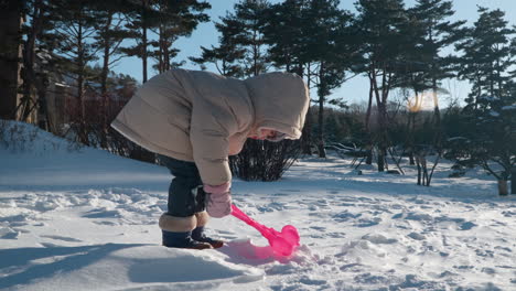 Glückliches-Kleines-Mädchen,-Das-Mit-Schnee-Spielt-Und-Im-Winterpark-Schneeballskulpturen-In-Entenform-Herstellt