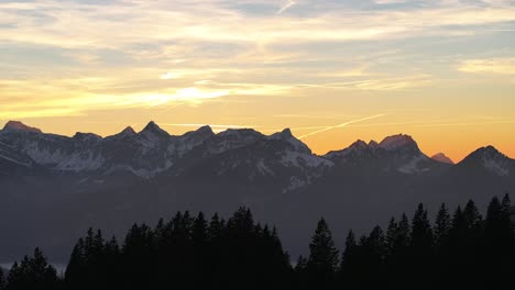 Drone-flies-over-mountains-and-in-the-distance-high-mountains-with-snow-in-Amden,-Weesen,-Glarus,-Switzerland,-sunrise-mood