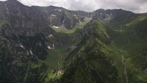 Üppige-Bucegi-Berge-Mit-Grünen-Hängen-Unter-Einem-Wolkigen-Himmel,-Luftaufnahme