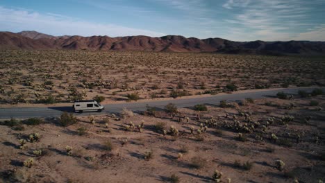 Ein-Mercedes-Sprinter-Van-Fährt-Auf-Einer-Straße-Im-Joshua-Tree-Nationalpark,-Während-Ihm-Eine-Drohne-Folgt