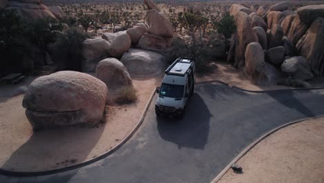 Ein-Mercedes-Sprinter-Van-Parkt-Im-Joshua-Tree-Nationalpark,-Während-Eine-Drohne-Ihn-Umkreist