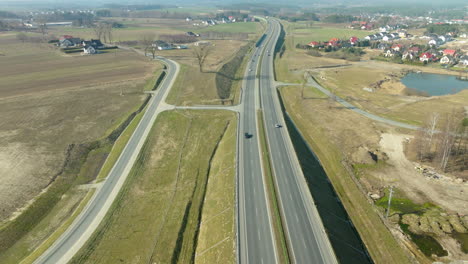 Aerial-view-of-a-highway-interchange-in-a-rural-setting-with-homes-and-a-pond