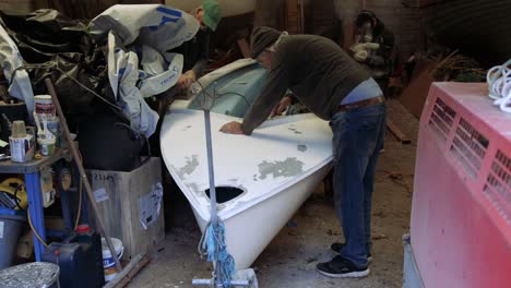 A-group-sanding-down-a-small-fiberglass-sailboat-Timelapse