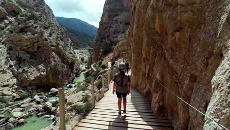 Woman-hiker-walking-mountain-trail-wooden-deck-by-the-mountainous-side-Spain