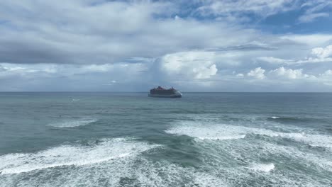 Waves-breaking-on-coast-with-cruise-ship-in-background