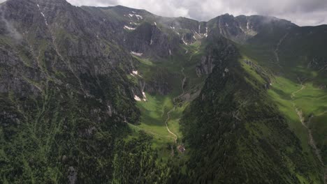 Lush-green-Malaiesti-Valley-in-the-Bucegi-Mountains-with-cloudy-skies,-aerial-view