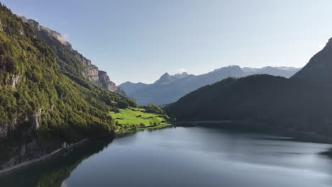 Drone-flying-over-Klöntalersee-Vorderglärnisch-Glarus-Switzerland,-high-mountains-blue-sky-and-lake
