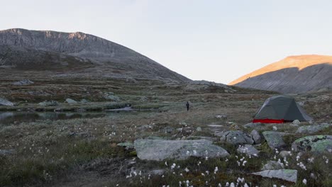 Solo-male-backpacker-hiking-in-autumnal-Scandinavian-tundra-landscape-in-front-of-tent