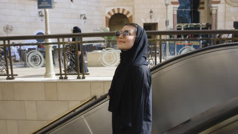 Mujer-Musulmana-Alegre-En-Las-Escaleras-Mecánicas-Del-Hotel-Anjum