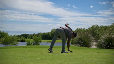 Slow-motion-of-a-latin-mexican-golfer-wearing-an-adidas-grey-outfit-relocating-his-tee-and-ball-for-the-drive