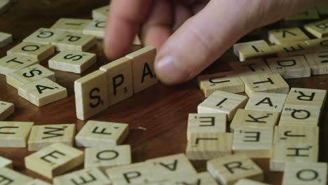 Mann-Legt-Scrabble-Buchstabensteine-Hochkant,-Um-Im-Spiel-Das-Wort-„Spanien“-Zu-Bilden