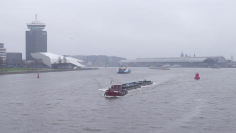 Low-angled-backwards-drone-shot-Amsterdam-IJ-revealing-Adam-tower-and-ship