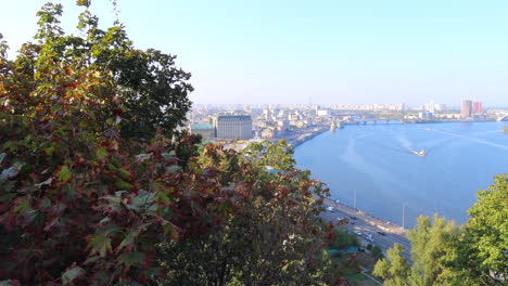 Beautiful-view-from-the-Glass-Bridge-on-the-famous-Dnipro-River-in-Kyiv-city-Ukraine,-buildings-and-trees-on-a-sunny-day,-4K-shot