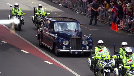 British-royal-car-is-escorted-by-police-officers-on-motorbikes-down-Adelaide-Street,-with-crowds-lining-the-street-for-annual-tradition-Anzac-Day-parade