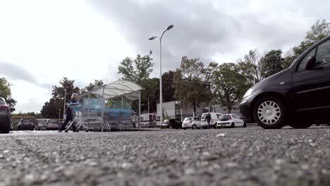 Returning-shopping-cart-on-parking-lot-seen-from-a-car-park-spot-low-angle