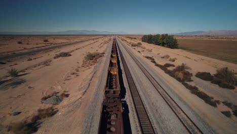 Eine-Drohne,-Die-In-Der-Nähe-Eines-Verlassenen-Eisenbahnwaggons-In-Der-Wüste-Fliegt