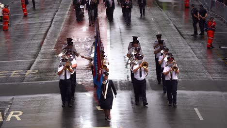 Una-Banda-De-Música-Actúa-Y-Marcha-Por-La-Calle-Adelaide-Con-Multitudes-Reunidas-A-Su-Lado,-En-Honor-A-La-Memoria-De-Los-Veteranos-Del-Día-De-Anzac.