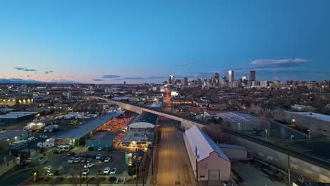 Blue-hour-glow-with-yellow-building-lights-illuminate-street,-Denver-Colorado-downtown-off-in-distance-at-dusk