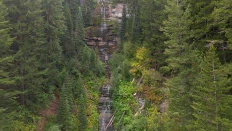 Luftaufnahme-Des-Wassers-Eines-Wasserfalls,-Der-Mitten-Im-Grünen-Wald-über-Die-Felsen-Stürzt