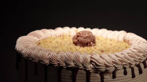Nahaufnahme-Einer-Detailaufnahme-Eines-Ferrero-Rocher-Kuchens,-Einer-Leckeren-Versuchung-Auf-Einem-Plattenteller-Mit-Schwarzer-Hintergrundschleife-Und-Schokolade-Obendrauf