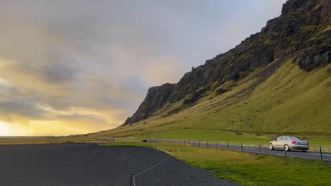 Icelandic-landscape-with-green-hills-and-road-under-dramatic-sunset-sky