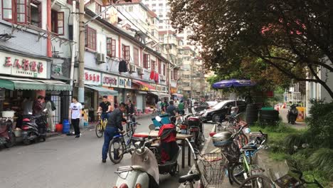 Calle-Muy-Transitada-En-Shanghai,-China,-Con-Mucha-Gente,-Bicicletas,-Motocicletas-Y-Gente.