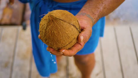 The-man-entertains-the-audience-by-breaking-the-coconut-with-his-hands,-using-his-old-and-unique-technique