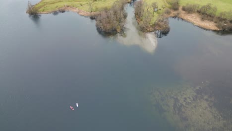 Vista-Aérea-De-Canoas-En-Un-Lago-Tranquilo-Cerca-Del-Pueblo-De-Grasmere-En-Cumbria,-Inglaterra